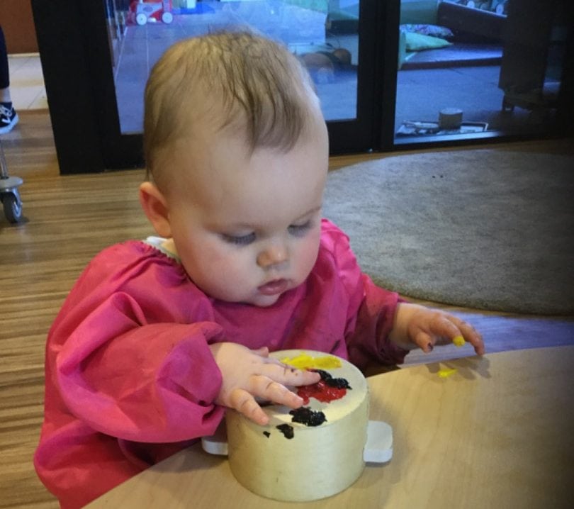 A baby playing with paint