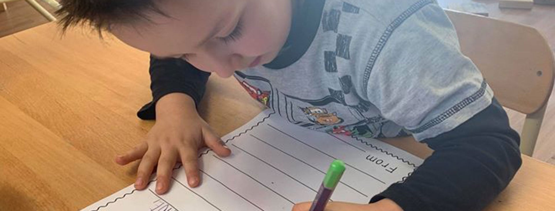 A young boy writing a letter