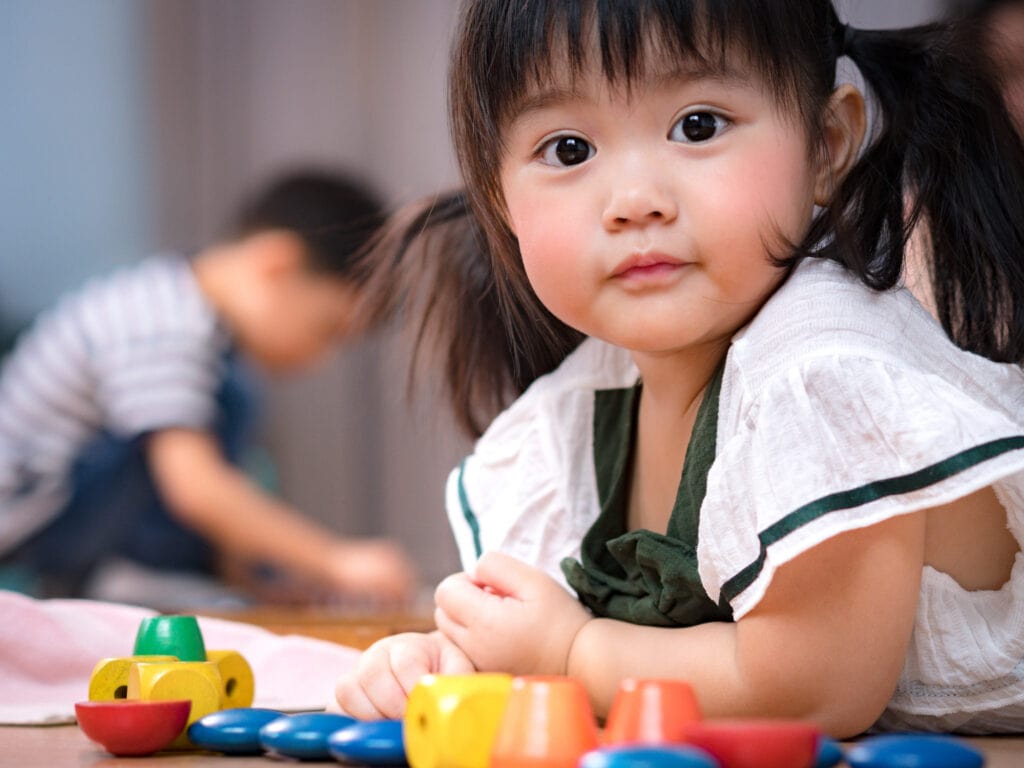 Portrait of cute Asian preschool age girl looking at camera in Montessori classroom