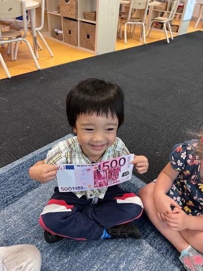 A young boy holding a $500 note