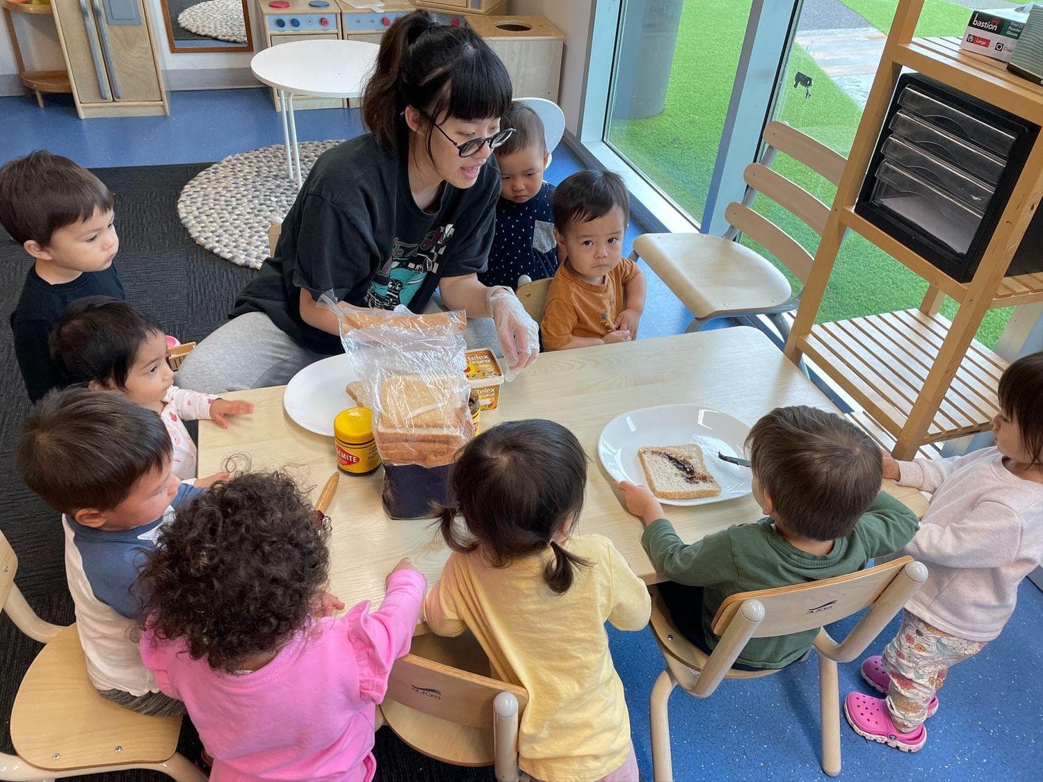 Childcare instructor talking to children round a table about eating