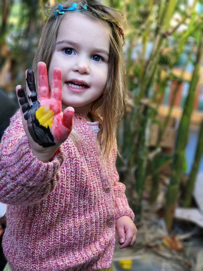 child celebrating reconciliation week with a painted hand